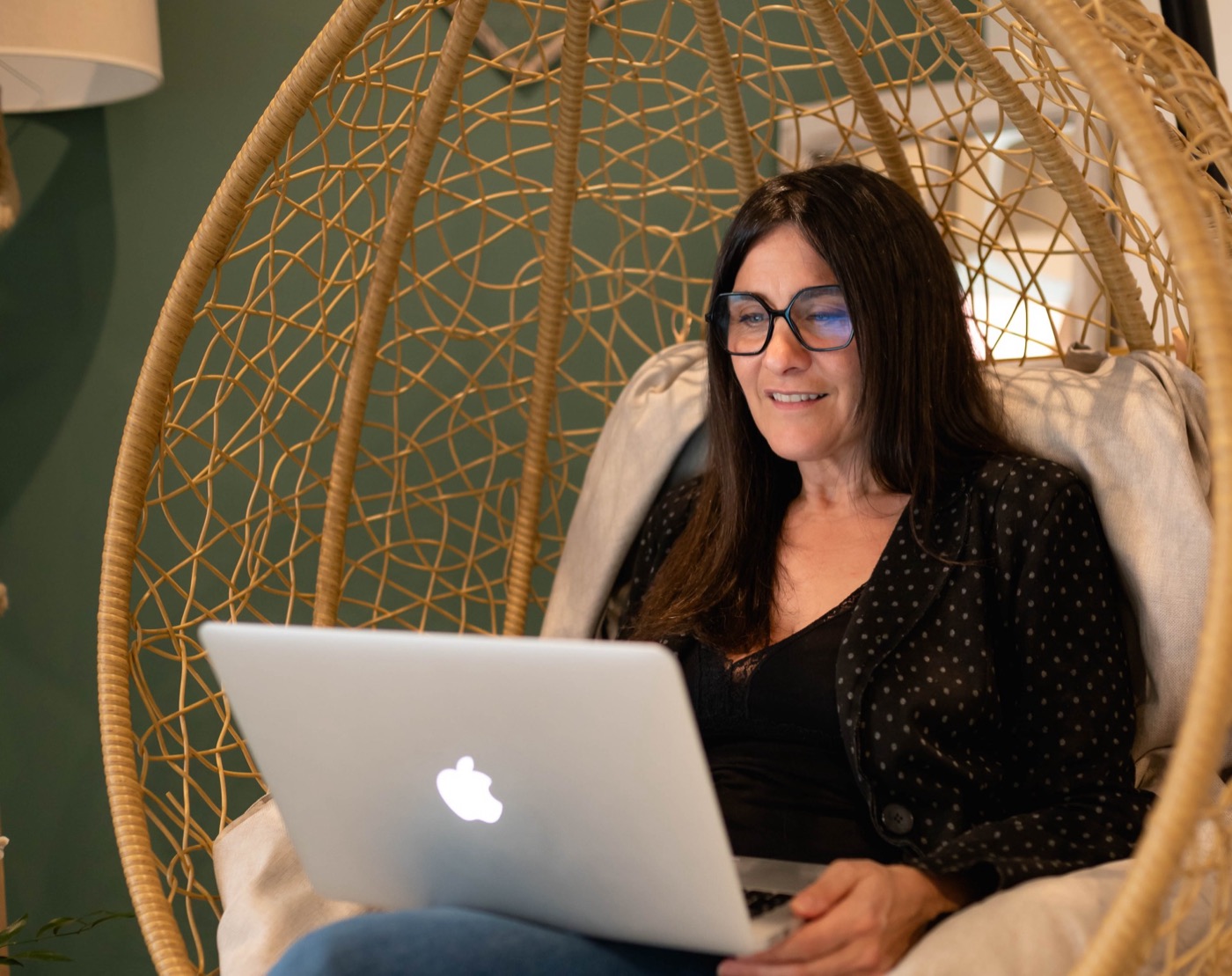 Sandrine dans un fauteuil en rotin, devant son ordinateur